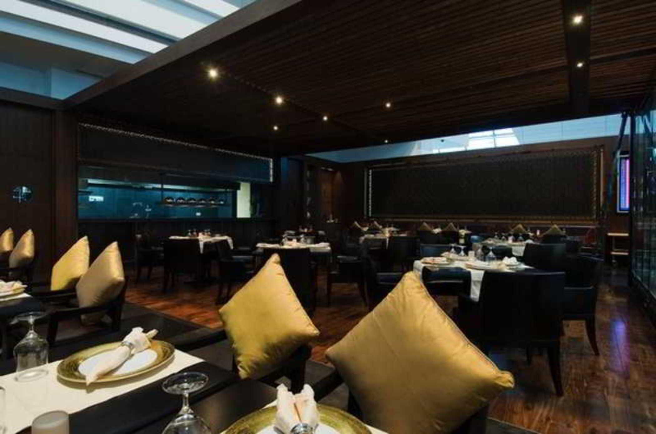 Dubai International Terminal Hotel Restaurant photo The photo depicts a modern restaurant interior. It features a spacious dining area with elegant wooden paneling and a contemporary design. The tables are neatly set with white tablecloths and elegant dishware. There are black chairs, some adorned wit