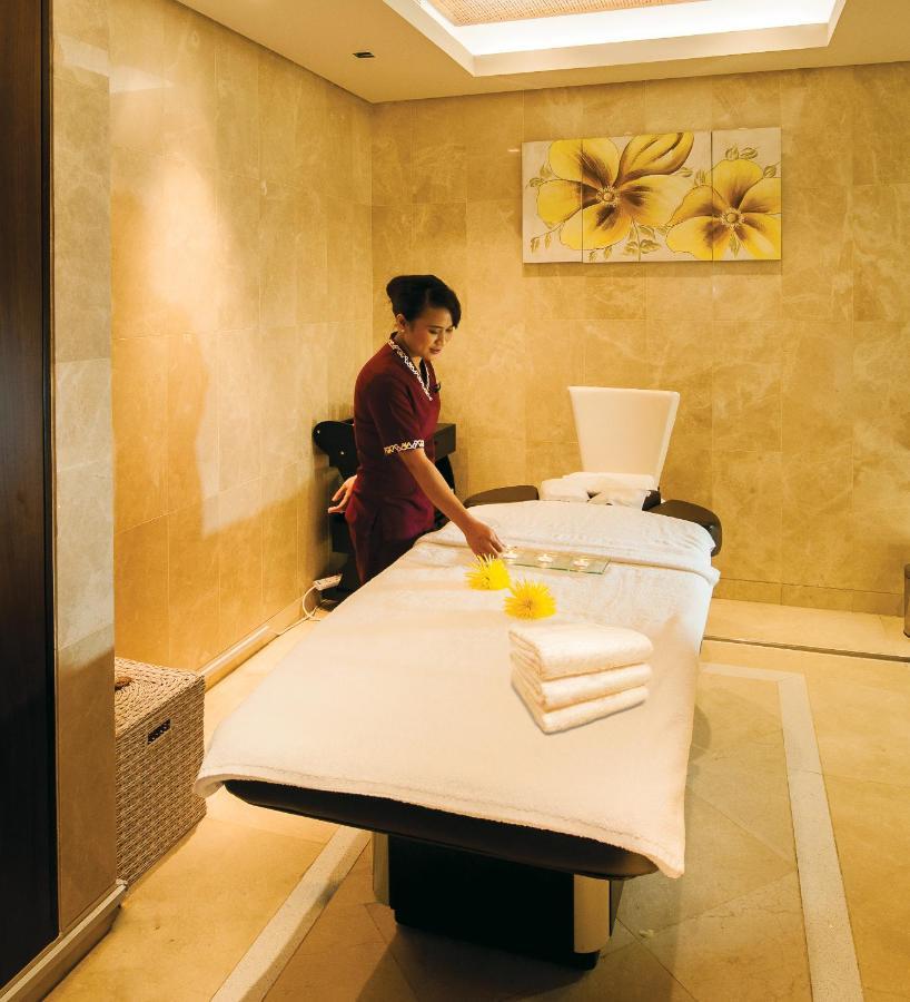 Dubai International Terminal Hotel Exterior photo The photo shows a spa setting with a massage table in a soothing environment. A staff member, dressed in a uniform, is preparing the table for a treatment. There are neatly folded towels placed on the table, and a tray with some items, possibly for a